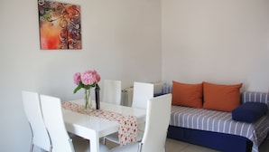 A dining area with a white table and chairs, a vase with flowers, and a colorful abstract painting on the wall. - Apartment in Vodice with Seaview, Balcony, Air condition, WIFI (612-4) (Vodice)