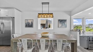 A modern kitchen with a wooden island, white chairs, a large bowl, and a hanging light fixture. - Waterfront Firepit Game Room at Legacy Beach House (Point Pleasant Beach)