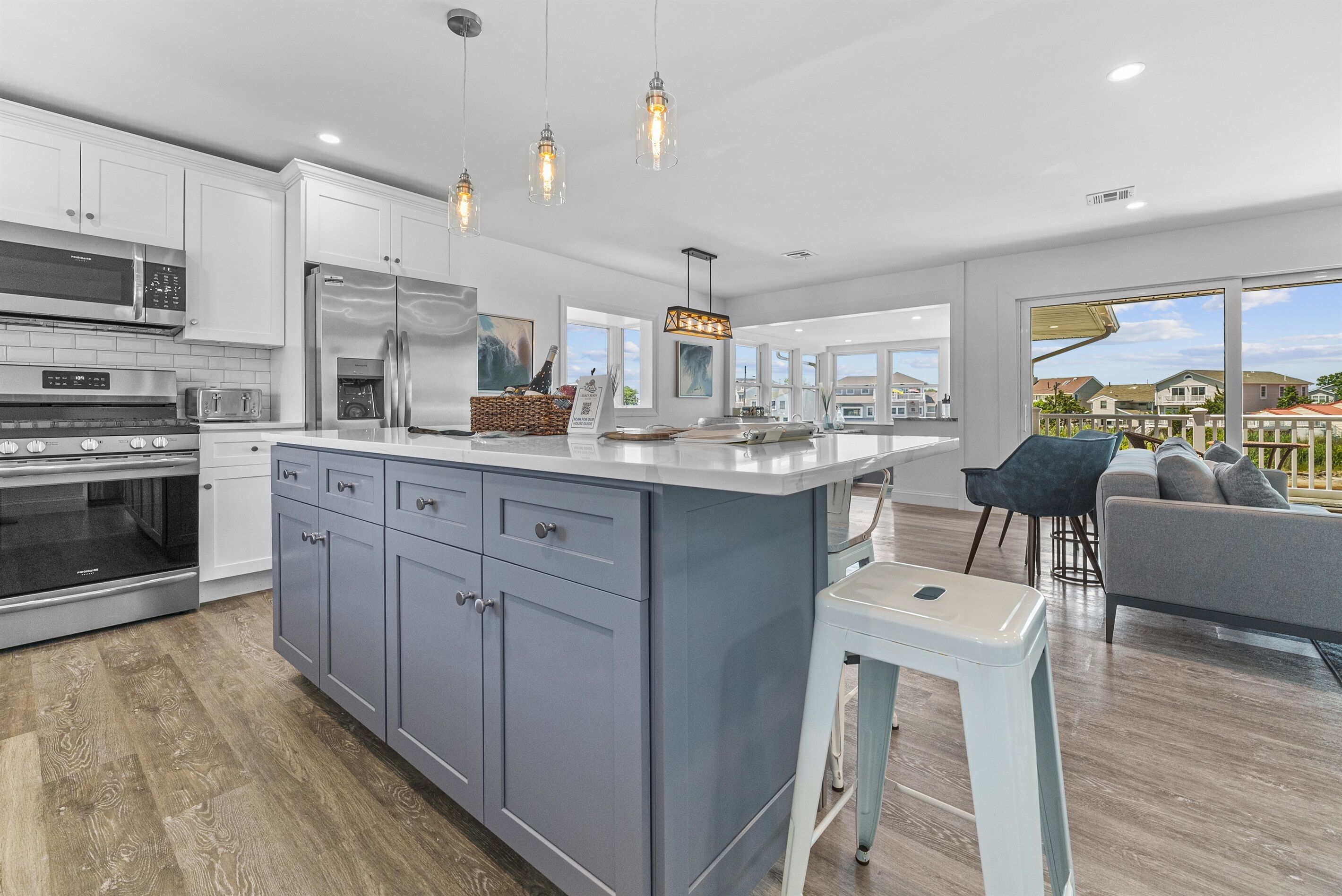 A modern kitchen with grey cabinets, stainless steel appliances, and pendant lighting.