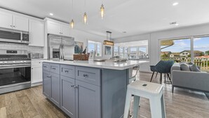 A modern kitchen with grey cabinets, stainless steel appliances, and pendant lighting. - Waterfront Firepit Game Room at Legacy Beach House (Point Pleasant Beach)