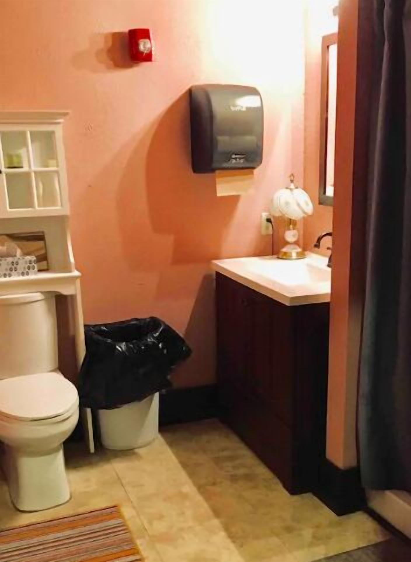A small bathroom with a toilet, sink, and a trash bin.