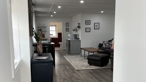 A spacious living area with a dark wood floor, a dining table, and a seating area with a sofa and ottoman. - Step into downtown, 5 minutes drive to Luray Caverns, 15 to Thorton Gap entrance (Luray)