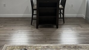 A modern living room with a dark wooden dining table, two chairs, a flat-screen TV mounted on the wall, and two windows with blinds. - Step into downtown, 5 minutes drive to Luray Caverns, 15 to Thorton Gap entrance (Luray)