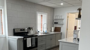 A modern kitchen with grey cabinets, a stainless steel stove, and a wooden dining table. - Step into downtown, 5 minutes drive to Luray Caverns, 15 to Thorton Gap entrance (Luray)