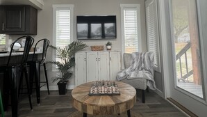 Ein Essbereich mit Holztisch, Stühlen, einem Blumentopf und einem Fernseher über einem weißen Schrank.
