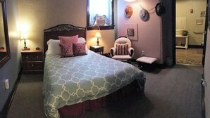 Ein Schlafzimmer mit einem Bett, Nachttischen, einem Sessel und einer Lampe.