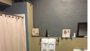 Ein Badezimmer mit Holzboden, Waschbecken, Spiegel und Duschvorhang.