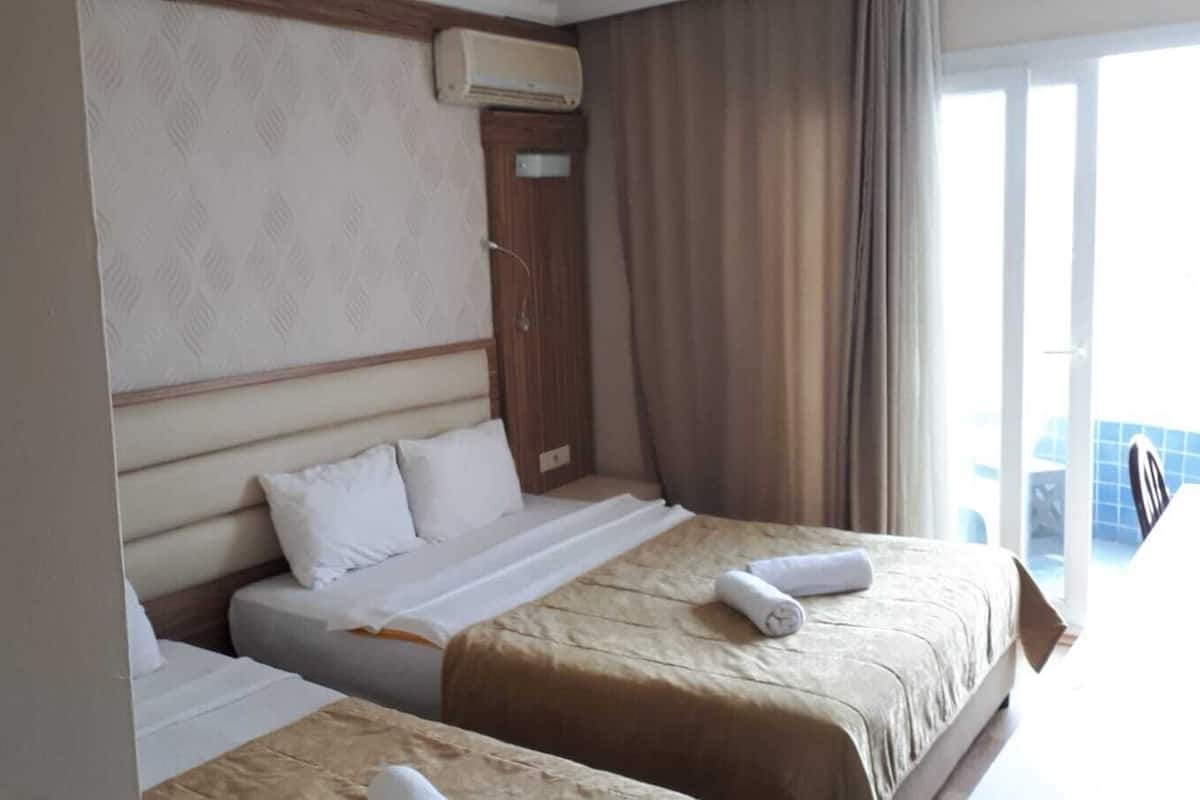 Une chambre d’hôtel avec deux lits, une fenêtre avec des rideaux et un climatiseur fixé au mur.