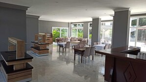 A spacious dining area with multiple tables and chairs, large windows, and a modern design. - Moonstar Hotel (Kusadasi)