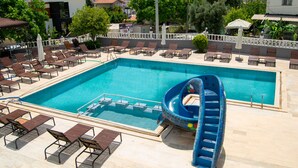 A swimming pool with a slide, lounge chairs, and a view of the surrounding area. - Moonstar Hotel (Kusadasi)