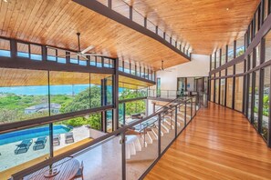 Un intérieur moderne avec un plafond en bois, des murs en verre et une vue sur une piscine.