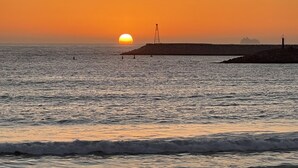 Ein Sonnenuntergang über dem Meer mit einem Steg und einem Schiff in der Ferne.