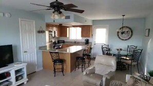 A spacious living area with a central island, a dining table with chairs, a sofa, and a TV stand. - Cozy 2-bedroom stay with great amenities (Panama City Beach)