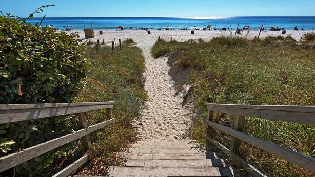 A wooden staircase leading to a sandy beach with a clear blue sky. - Cozy 2-bedroom stay with great amenities (Panama City Beach)