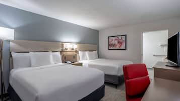 Una habitación de hotel con dos camas, un escritorio, un televisor y una silla roja.