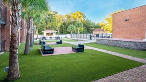 A courtyard with artificial grass, outdoor seating, and palm trees.