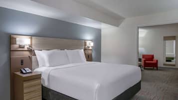 Habitación de hotel con una cama grande, lámparas de noche, un teléfono en la mesita y una silla roja en la esquina.