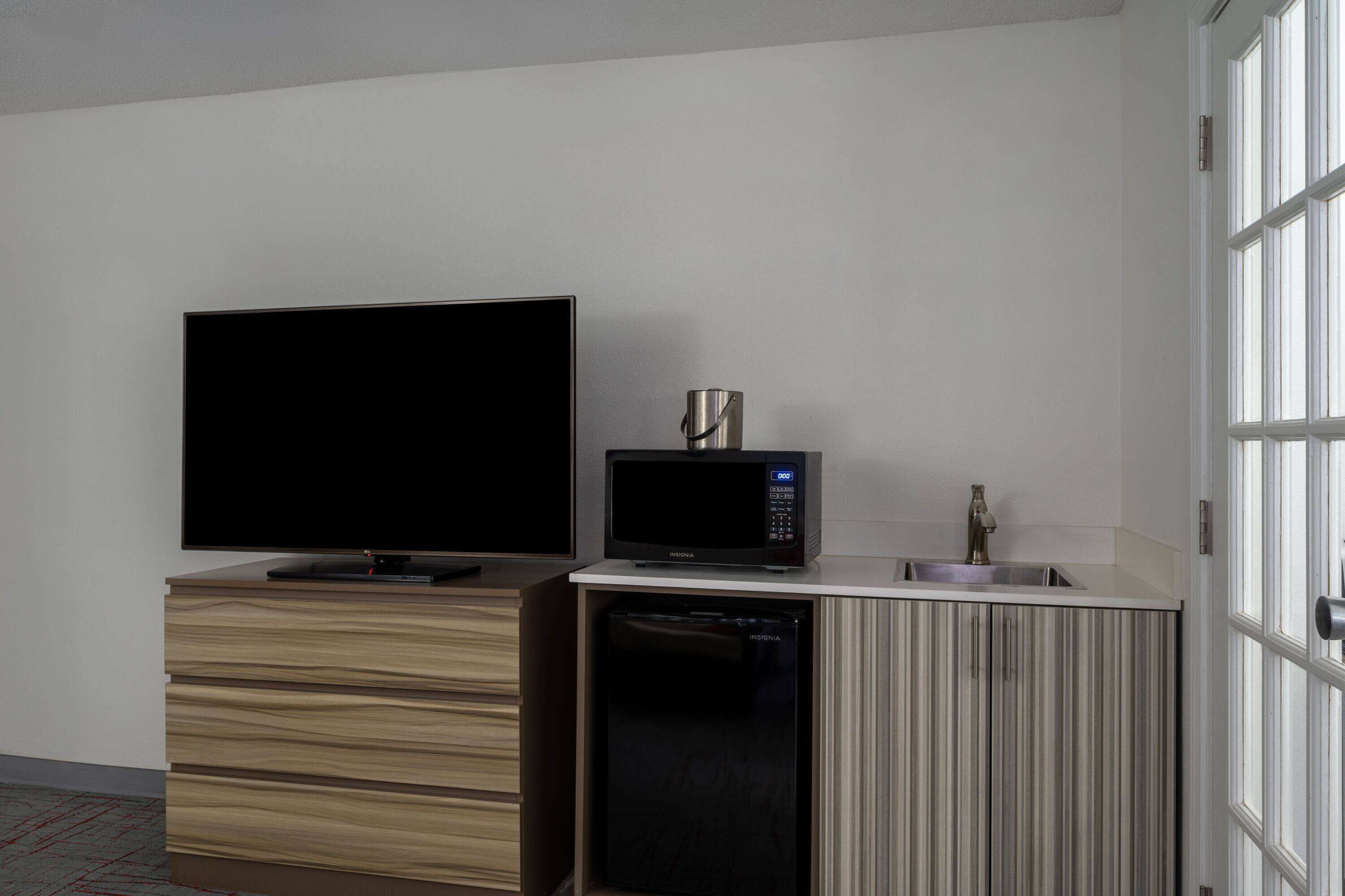 A compact living space with a flat-screen TV, a microwave, and a built-in dishwasher.