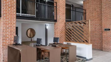 Un espacio de oficina moderno con paredes de ladrillo, un área de escritorio de madera y una señalización de ascensor visible.