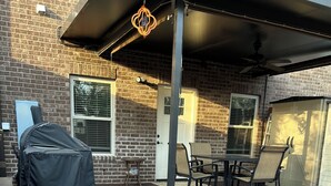 A covered patio area with a brick floor, a barbecue grill, and outdoor furniture. - High End Townhouse 12 min walk to Campus and Downtown (Auburn)