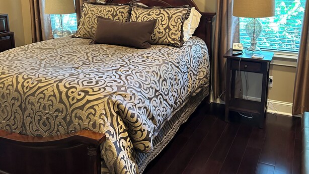 A bedroom with a large bed, a ceiling fan, a window with curtains, and a nightstand with a lamp. - High End Townhouse 12 min walk to Campus and Downtown (Auburn)