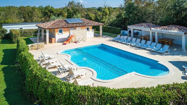 A swimming pool with lounge chairs, a slide, and a covered seating area.