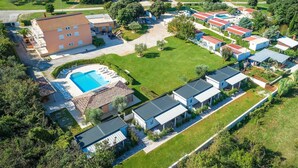 An aerial view of a residential area with a swimming pool, multiple houses, and a large building with a red roof.