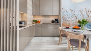 A modern kitchen with grey cabinets, a wooden countertop, and a dining area with a round table and chairs. - Seaside Apartamenty-Mielno  (Mielno)