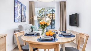 A dining area with a round table, chairs, and a vase with flowers. - Seaside Apartamenty-Mielno  (Mielno)