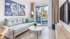 A modern living room with a grey sofa, a round white coffee table, and two paintings on the wall. - Seaside Apartamenty-Mielno  (Mielno)