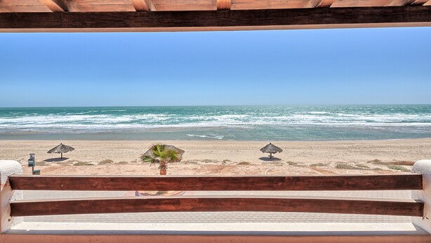 Un banco de madera con vista a una playa y el océano al fondo.