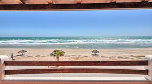Un banco de madera con vista a una playa y el océano al fondo.