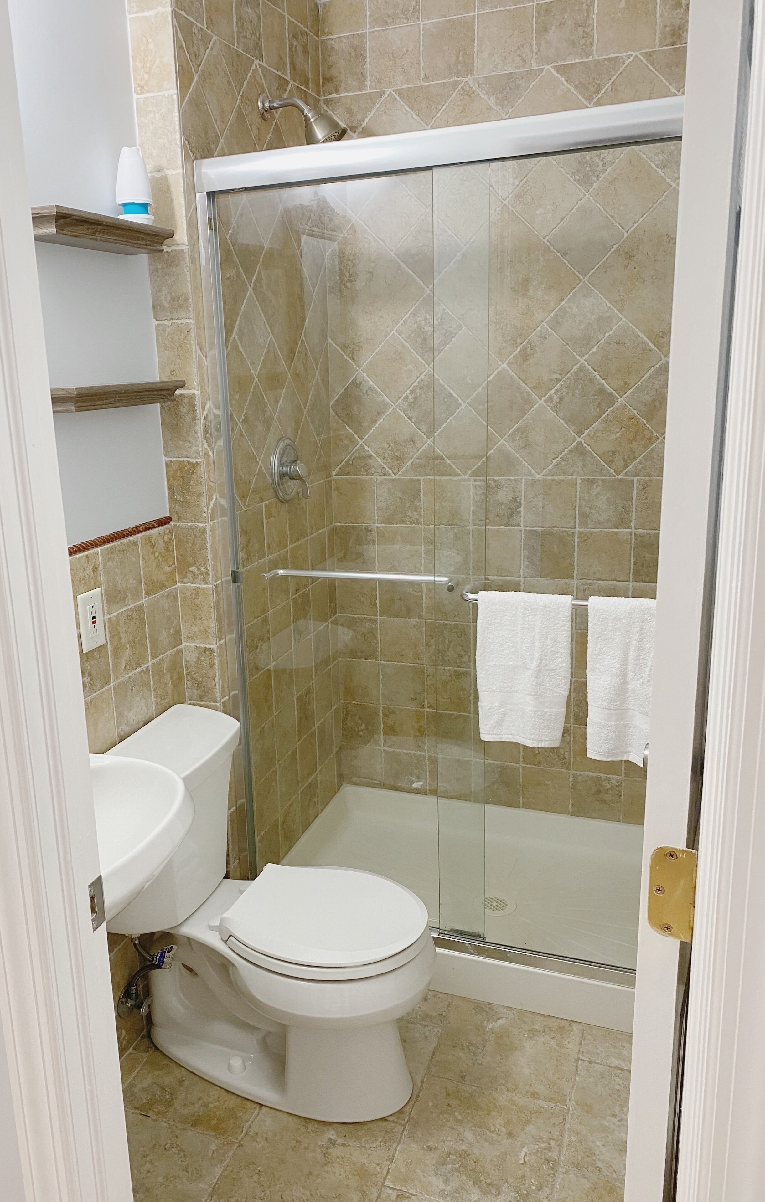 A bathroom with a glass-enclosed shower, a toilet, and a sink.