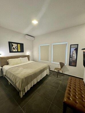 A modern bedroom with a bed, bedside tables, a chair, and a bench.