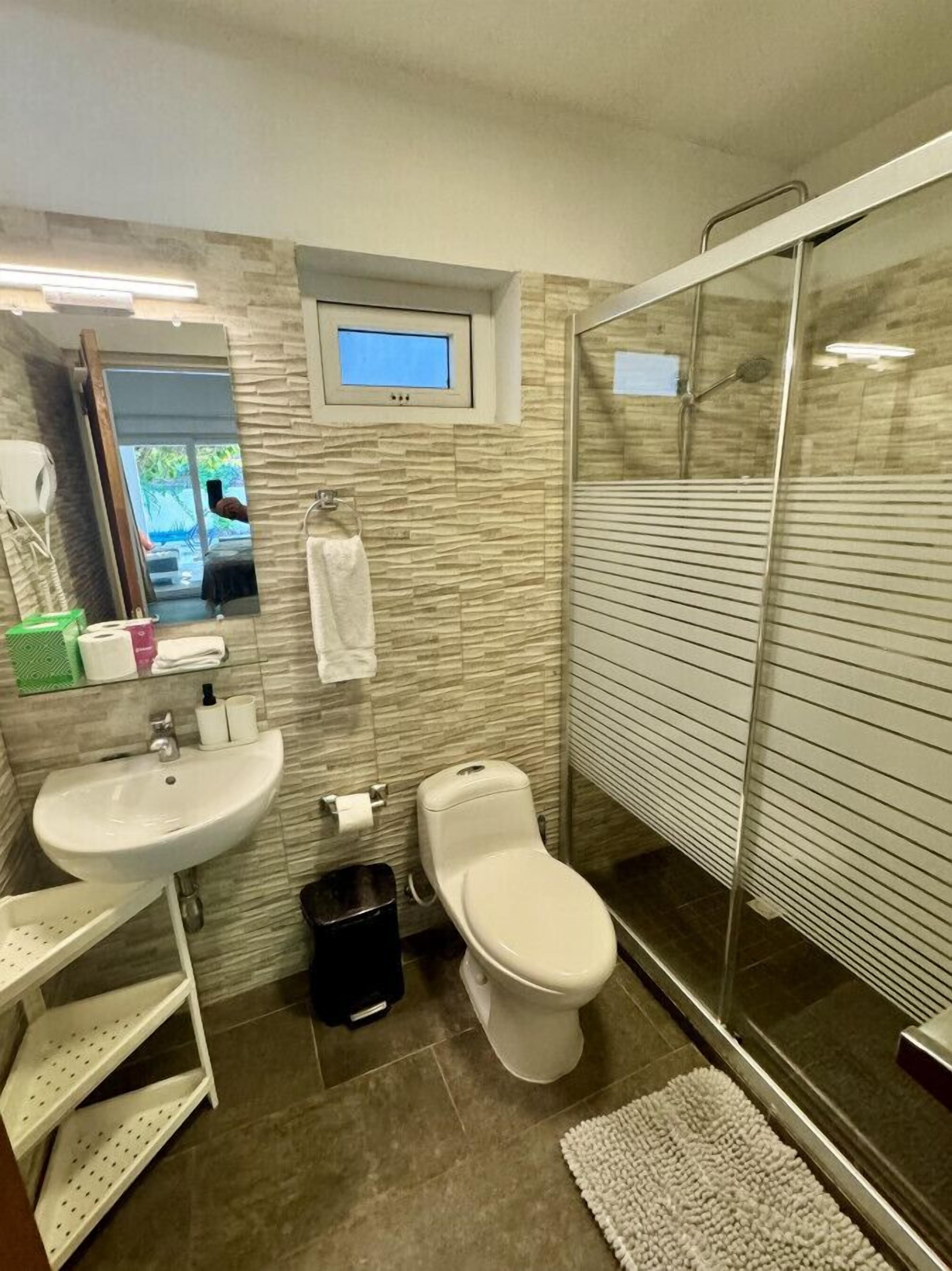 A modern bathroom with a sink, toilet, and shower.