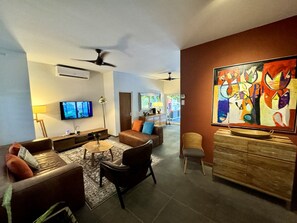 A modern living room with a sofa set, a coffee table, a TV, and a painting on the wall.