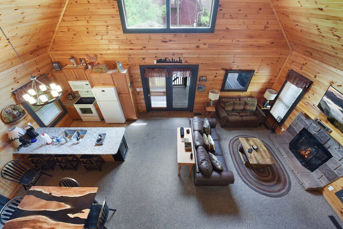Een knus interieur van een chalet met een eethoek, keuken, woonkamer en open haard.
