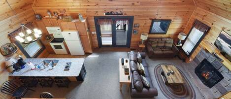 Een knus interieur van een chalet met een eethoek, keuken, woonkamer en open haard.