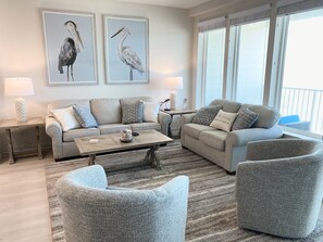 Een woonkamer met een bank, twee fauteuils, een salontafel en twee lampen. Twee vogelschilderijen hangen in lijsten aan de muur.