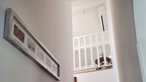 A wooden staircase leading to a landing with a white railing and a framed picture on the wall. - Apartment (Caux)