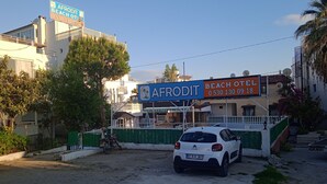 A building with a sign for 'AFRODIT BEACH HOTEL' and a parked car in front. - Afrodit Beach Otel (Kusadasi)