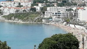 A coastal cityscape with a beach, buildings, and a large tree. - Afrodit Beach Otel (Kusadasi)