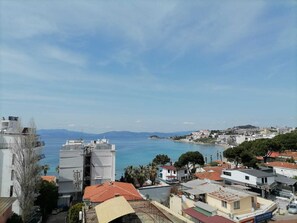 A coastal town with buildings overlooking the sea, including a large industrial structure and residential areas with visible signage.