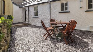 A white building with a tiled roof, a gravel patio, and a wooden table with chairs. - Awelfa (Newport)