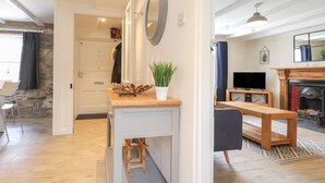 A modern living room with a fireplace, a TV, and a dining area with a bench and table. - Awelfa (Newport)