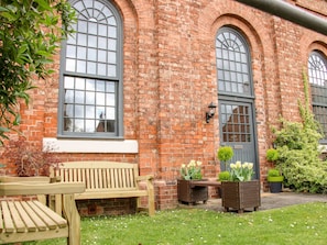 A brick building with large arched windows and a wooden bench in the foreground. - 6 The Engine Shed (Shrewsbury)