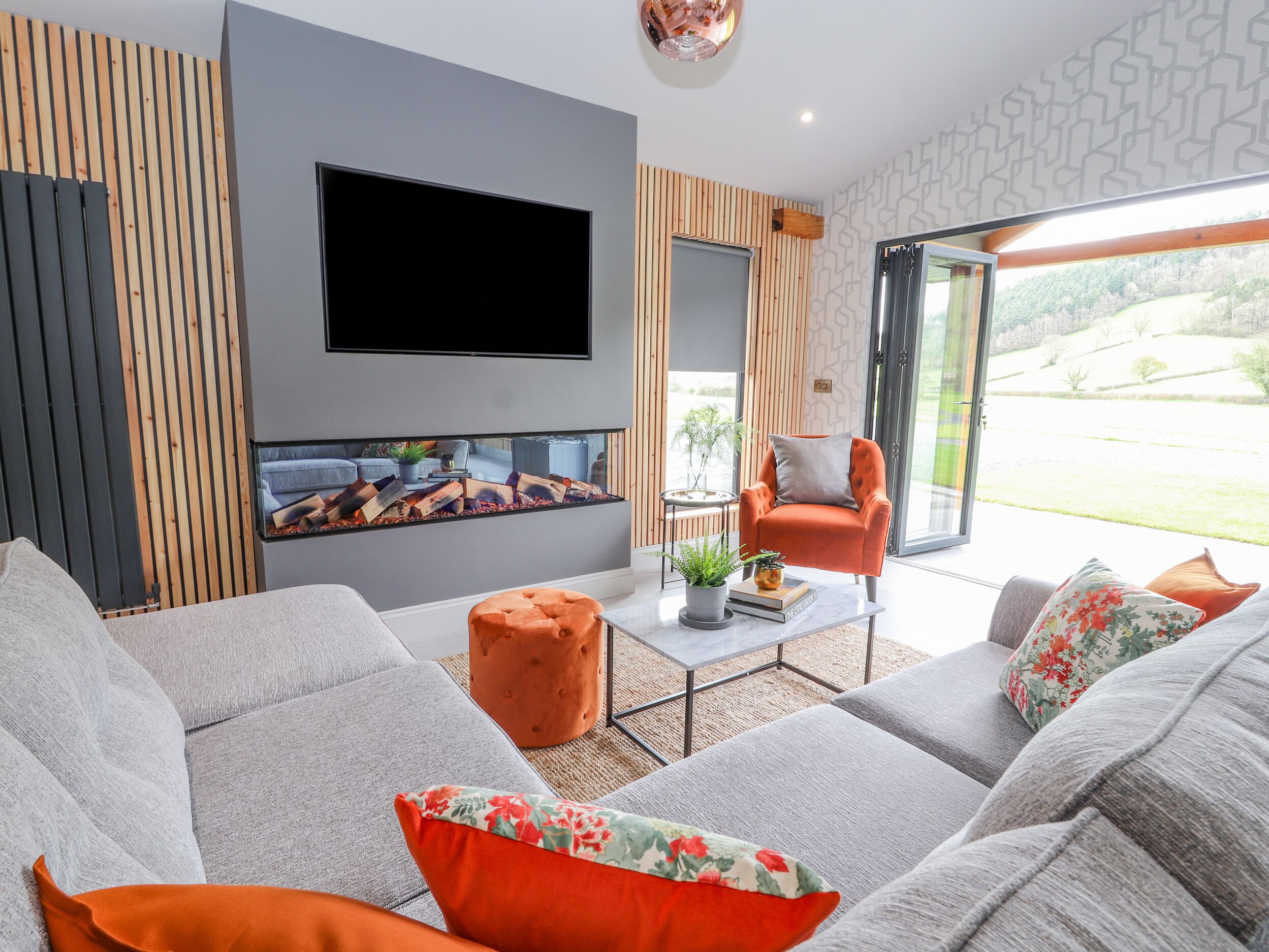A modern living room with a large flat-screen TV, a fireplace, and a comfortable seating area with sofas and a coffee table.
