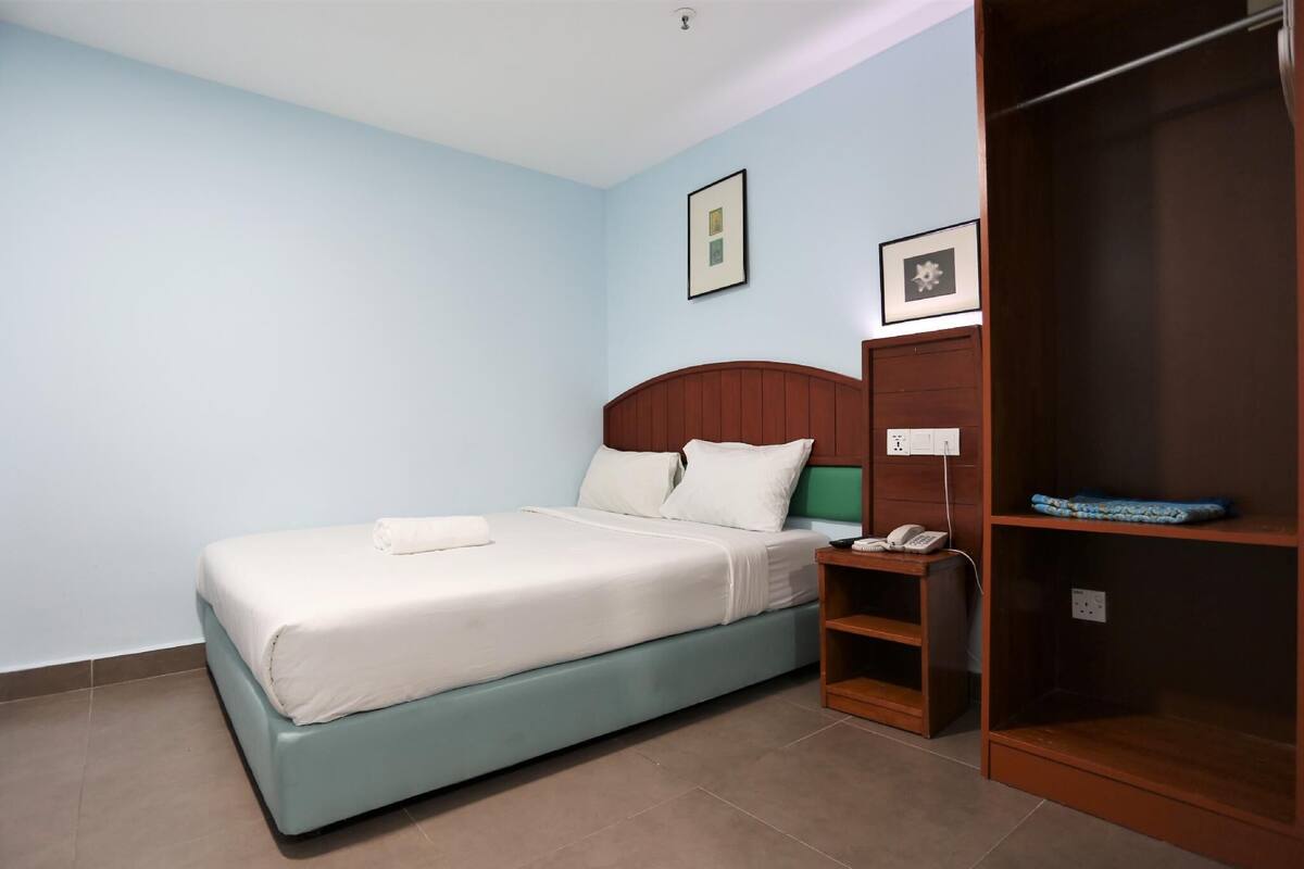 Un dormitorio con cama, armario de madera, mesita de noche y teléfono en la pared.