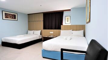 A hotel room with two single beds, a desk with a chair, and a large window with curtains.