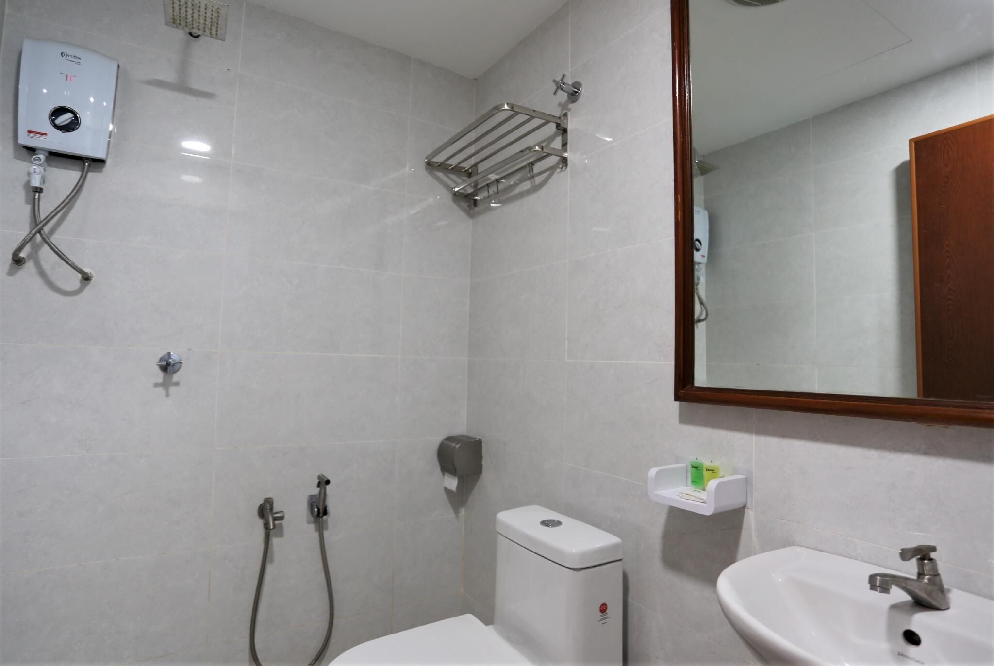 A bathroom with a toilet, bidet, sink, and a shower with a towel rack.